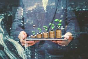 Businessman holding a tablet with coins stack and tree,Lucky economic growth concept photo