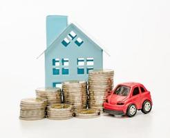 pilas de monedas y coche y casa sobre fondo blanco, ahorro empresarial y concepto de inversión foto