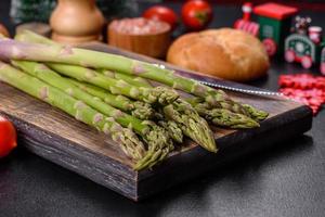 Delicious fresh raw green asparagus stalks on wooden cutting board photo
