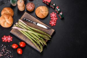 Delicious fresh raw green asparagus stalks on wooden cutting board