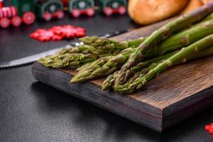 Delicious fresh raw green asparagus stalks on wooden cutting board