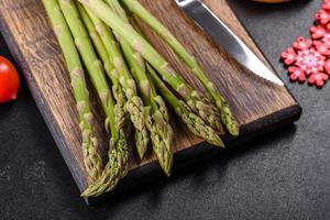 Delicious fresh raw green asparagus stalks on wooden cutting board photo