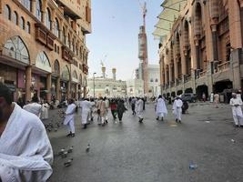 la meca, arabia saudita, junio de 2022 - las palomas en la carretera frente a la mezquita al haram en la meca son el centro de atención para los visitantes del exterior. los visitantes también les dan grano y agua. foto