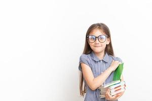 una niña de 7 años con gafas y libros con cara de sorpresa. educación infantil, concepto de aprendizaje con espacio de copia foto