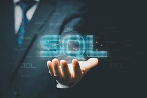 Businessman hand showing SQL word and SQL or Structured Query Language code on background. photo