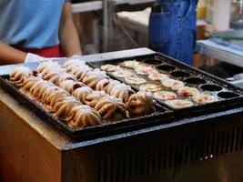 calamares frescos a la parrilla en parrilla de carbón, pulpo asado en plato blanco. mariscos en comida callejera, tailandia. foto