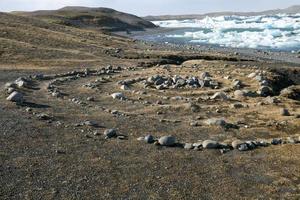 guijarros en espiral al borde del lago jakulsarlon con icebergs en islandia foto