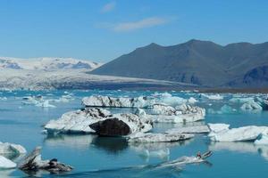 Zodiac boat sailing on the Jokulsarlon lake between bright clear blue icebergs in Iceland photo