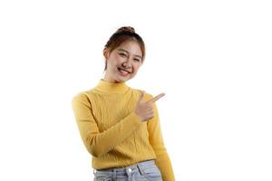 Portrait of a beautiful Asian woman in a yellow shirt standing and pointing. portrait concept used for advertisement and signage, isolated over the blank background, copy space. photo