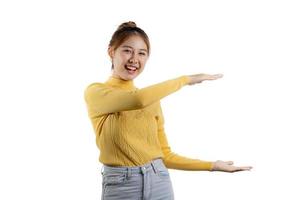 Portrait of a beautiful Asian woman in a yellow shirt standing and pointing. portrait concept used for advertisement and signage, isolated over the blank background, copy space. photo