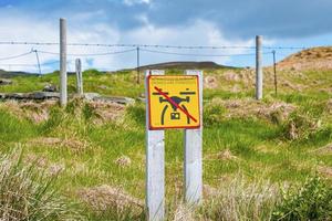 No drone flying sign on grassy landscape in protected valley against blue sky photo