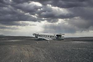 paisaje nuboso sobre un accidente de avión roto en la playa de arena negra en solheimasandur foto