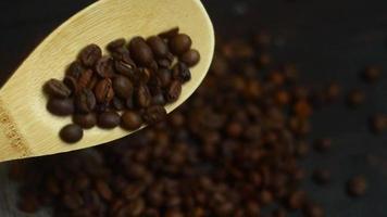 A full wooden spoon of roasted coffee beans. Falling coffee beans from wooden spoon in on a coffee brown background. Eco food concept. video