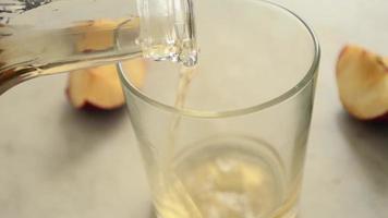 l'uomo sta versando un succo di mela da un decanter in un bicchiere, primo piano. video