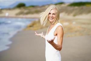 Happy mature woman walking on the beach, spending her leisure time, enjoying her free time photo