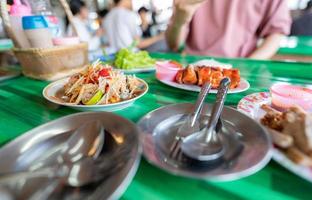 Spicy green papaya salad or Som Tum with Thai rice noodles. Street food with hot and spicy dish in Thailand. The famous local Thai street food. Thai Esarn cuisine. Papaya salad with grilled chicken. photo