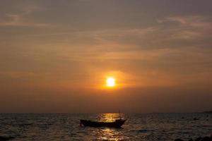 Silhouette of a fishing boat in the middle of the picture, in the evening there is a sunset at the sea photo
