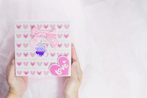 High angle view of two hands holding a gift box with a heart pattern photo