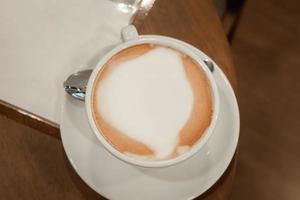 Frothy coffee and stainless steel spoons are placed on the table in the coffee shop.copy space photo