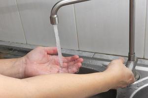 The hand that is turning on the water and the other hand is getting the water.Hygiene concept. photo