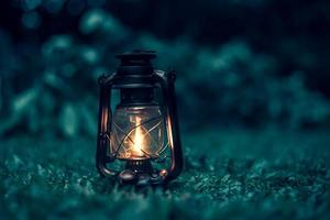 lámpara de queroseno antigua en la hierba en el bosque por la noche. enfoque suave. foto