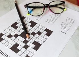 Pencil and glasses on the paper with solved number crossword puzzle