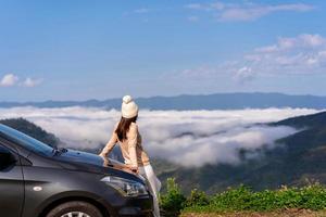 Young woman travelers with car watching a beautiful sea of fog over the mountain while travel driving road trip on vacation photo