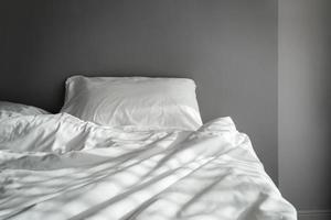 The blankets on the crumpled mattress in the empty dark bedroom photo