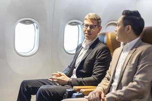 un hombre de negocios caucásico viaja con ropa formal y su compañero se sienta cómodamente en el avión con un asiento de clase ejecutiva con espacio para copiar foto