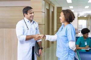 Team of diversity doctor and nurse is handshaking after working on patient medical record for precise care plan with experienced senior physician specialist photo
