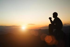 Man praying at sunset mountains raised hands Travel Lifestyle spiritual relaxation emotional concept, Freedom and travel adventure. photo