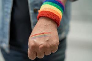Asian lady wearing rainbow flag wristbands, symbol of LGBT pride month celebrate annual in June social of gay, lesbian, bisexual, transgender, human rights. photo