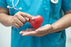 Doctor holding a red heart in hospital ward, healthy strong medical concept. photo