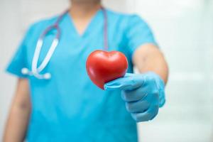 Doctor holding a red heart in hospital ward, healthy strong medical concept. photo