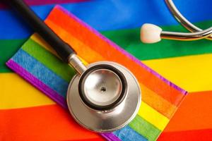 Black stethoscope on rainbow flag background, symbol of LGBT pride month celebrate annual in June social, symbol of gay, lesbian, bisexual, transgender, human rights and peace. photo