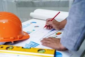 Architect or engineer working project accounting with graph and construction helmet in office, Construction account concept. photo
