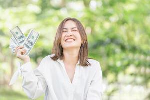 alegre joven independiente relajándose y sosteniendo billetes de dinero, mujer feliz sosteniendo y mostrando billetes de dinero foto