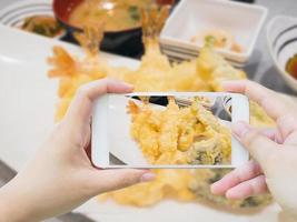 tomando fotos de gambas tempura en plato blanco