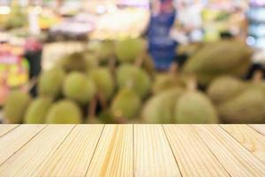 Wood table and Supermarket with durian fruit on shelves blurred background with bokeh photo