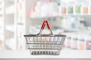 Empty shopping basket on pharmacy drugstore counter with blur shelves of medicine and vitamin supplements background photo