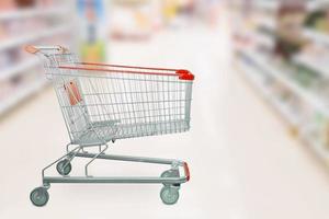 Empty red shopping cart with abstract blur supermarket discount store aisle and product shelves interior defocused background photo