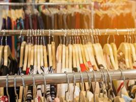 Clothes hang on rack shelf in clothing store photo