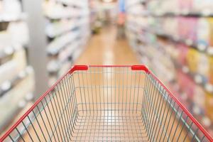 empty red shopping cart with abstract blur supermarket aisle defocused background photo