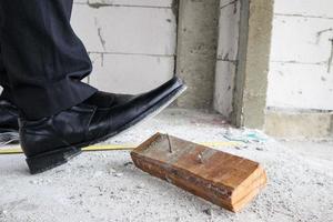 Construction worker with leather shoes steps on nail at house building site, work accident concept photo