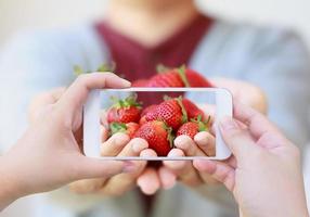 mujer tomando fotos de fresas frescas