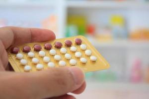 primer plano de las manos del farmacéutico sosteniendo píldoras anticonceptivas foto