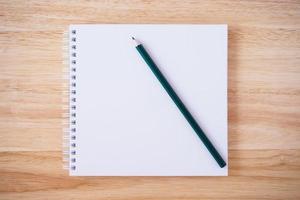 white cover notebook top view with pencil on brown wood desk photo