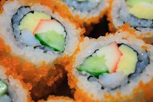 Sushi roll, row of California maki roll sushi with caviar on black plate photo