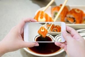 Taking photo of Salmon sushi in chopsticks