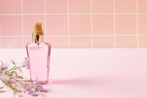 Pink perfume cosmetic bottle and natural flowers photo